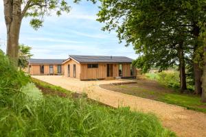 a large wooden building with trees in front of it at Avocet Lodge in Ingoldisthorpe