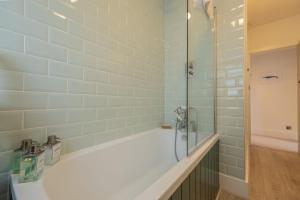 a bathroom with a shower and a bath tub at Tide Cottage WR in West Runton +39 photos