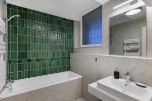 een badkamer met een wastafel, een bad en een spiegel bij Florin Apart Hotel in Boedapest