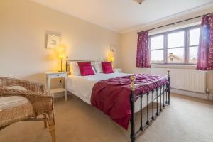 a bedroom with a bed with pink pillows and a window at Arisaig in Wells next the Sea
