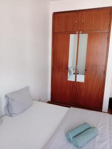 a bedroom with a bed with a wooden cabinet and a mirror at Cacilhas Mini Hostel in Cacilhas