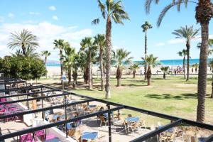 a view of the beach from the balcony of a resort with palm trees at Hotel Costa Azahar in Grao de Castellón