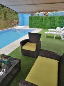 a patio with wicker chairs and a swimming pool at Quinta privada con cabaña y piscina temperada in Cartago