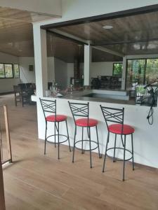 three bar stools with red seats in a kitchen at Quinta privada con cabaña y piscina temperada in Cartago