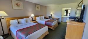 a hotel room with two beds and a flat screen tv at Ramada by Wyndham & Suites Warner Robins in Warner Robins