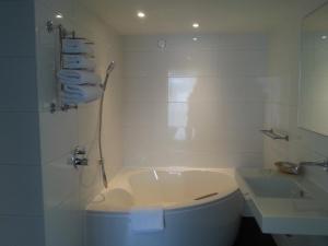 un bagno bianco con vasca e lavandino di Hotel Medemblik a Medemblik