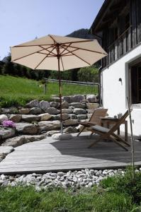 a patio with a chair and an umbrella at Alpen Charme - Chalet d'Hôtes et SPA in Gsteig
