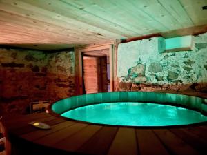 bañera de hidromasaje en una habitación con pared de piedra en Alpen Charme - Chalet d'Hôtes et SPA en Gsteig