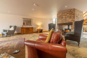 uma sala de estar com um sofá de couro e uma lareira em The Old English Barn em Bacton