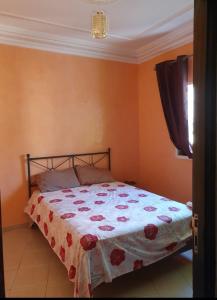 Schlafzimmer mit einem Bett mit einer roten und weißen Bettdecke in der Unterkunft Agadir in Agadir