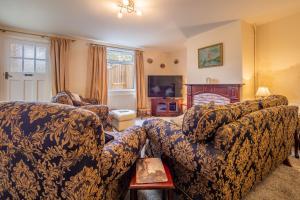 a living room with a couch and a tv at Margarets Cottage in Potter Heigham