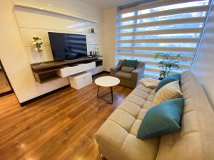 a living room with a couch and a flat screen tv at Suites Metropoli Bristol Parc in Quito