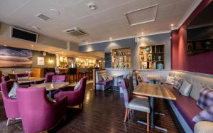 un restaurante con mesas de madera y sillas moradas en White Horse Inn en Balmedie