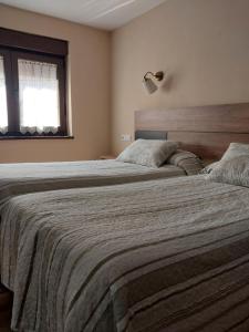 1 dormitorio con 2 camas y ventana en Hotel Rural Cabrales, en Carreña