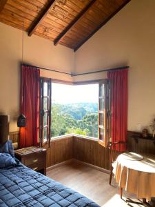 a bedroom with a bed and a large window at Chalé Recanto Bela Vista in Monte Verde