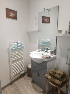 a white bathroom with a sink and a mirror at La longère de Suzanne in Arrest