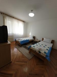 a room with two beds and a flat screen tv at Centar Apartment in Gevgelija