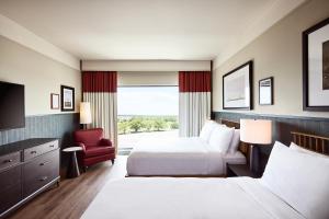 a hotel room with two beds and a chair at The Scarlet, Lincoln, a Tribute Portfolio Hotel in Lincoln