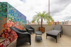 a balcony with chairs and tables and a palm tree at Monreale Express Ribeirão Preto in Ribeirão Preto