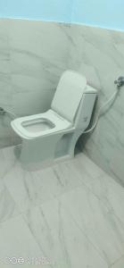 La salle de bains est pourvue de toilettes blanches et de murs en marbre. dans l'établissement OYO Hotel Sky Bird, à Pehowa