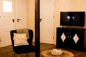 ein Wohnzimmer mit einem Stuhl und einem Flachbild-TV in der Unterkunft Sosnowy Strumyk 
