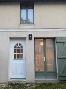 una casa con una puerta blanca y dos ventanas en Charmante petite maison, en Bourges