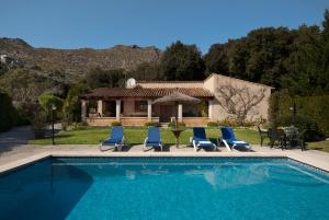 een zwembad met blauwe stoelen en een huis bij Villa Geroni in Pollença