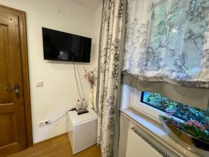 a room with a window with a television and a curtain at Airport Rooms Waldblick in Cologne