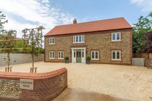 a brick house with a green door in a driveway at Limestone House in Burnham Market