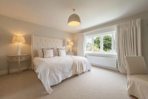 a white bedroom with a bed and a window at Limestone House in Burnham Market