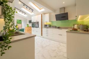 a kitchen with white cabinets and a green wall at Low Wood in West Runton