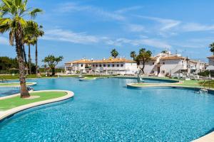 a swimming pool in a resort with palm trees and buildings at Casa lago jardin in Alicante