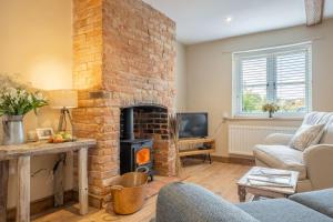 ein Wohnzimmer mit einem gemauerten Kamin in der Unterkunft Willow Cottage SC in South Creake