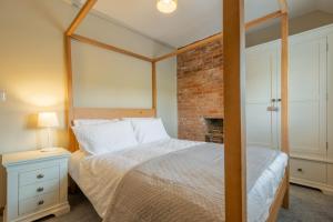 a bedroom with a canopy bed and a fireplace at Willow Cottage SC in South Creake