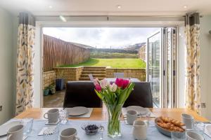 a table with pink flowers in a vase on it at Burbage View in Buxton