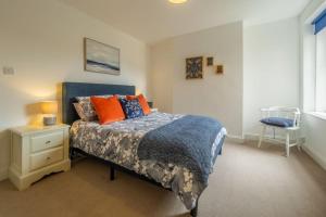 1 dormitorio con 1 cama con almohadas de color naranja y azul en Blue Skies Apartment, en Hunstanton