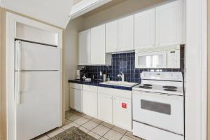 a kitchen with white cabinets and a white refrigerator at Duval Dream Loft on Duval in Key West +13 photos