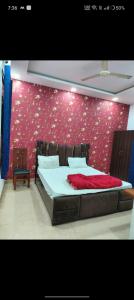 - une chambre avec un grand lit et un mur rouge dans l'établissement OYO The Rich Chair Hotel Restaurant And Banquet Hall, à Kaliānpur