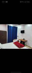 a bedroom with a bed with a table and a blue curtain at OYO The Rich Chair Hotel Restaurant And Banquet Hall in Kaliānpur