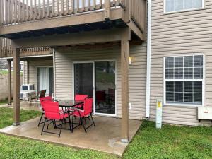 a patio with red chairs and a table in front of a house at New Remodeled Luxury Condo By The Lake, No Stairs! in Branson