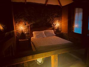 a bedroom with a bed and a stone wall at Alcohuaz Indomito in Alcoguaz