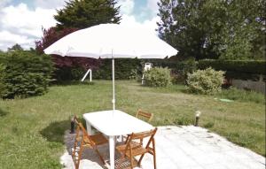 ein weißer Tisch mit zwei Stühlen und einem Sonnenschirm in der Unterkunft Amazing Home In Anneville Sur Mer in Anneville-sur-Mer + 17 Fotos