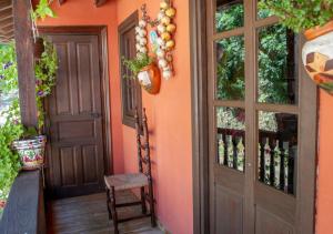 ein orangefarbenes Haus mit einer Tür und einem Stuhl in der Unterkunft Casa Rural La Aldea in Pola de Laviana