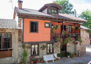 una casa naranja con un banco delante en Casa Rural La Aldea en Pola de Laviana