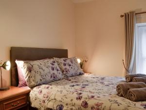 a bedroom with a bed with a floral comforter at Rhonas Cottage in Abergavenny
