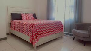 a bedroom with a bed with a red and white comforter at Weekendz- Cozy 2BRD Suite in Port Antonio