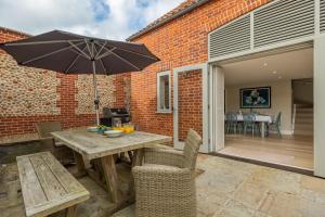 a patio with a wooden table with an umbrella at 1 Railway Cottages H in Holt
