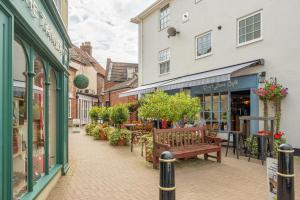 a street with shops and a bench in a city at 1 Railway Cottages H in Holt