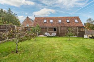 a house with a yard with trees and a fence at Cartshed Lodge in Hoveton