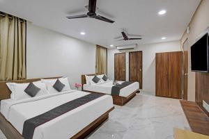 a bedroom with two beds and a flat screen tv at OYO Collection O Hotel Infini Palace in Surat